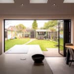 Thumbnail of http://Modern%20kitchen%20with%20island%20and%20adjacent%20dining%20area.%20Bi-fold%20doors%20open%20to%20a%20fenced%20backyard%20with%20a%20small%20path%20leading%20to%20a%20shed%20and%20garden.%20Skylights%20illuminate%20the%20space.