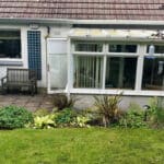 Thumbnail of http://A%20small%20backyard%20with%20a%20patio%20bench,%20greenery,%20and%20a%20glass%20conservatory%20attached%20to%20a%20house%20with%20a%20tiled%20roof.%20There%20is%20a%20bird%20feeder%20hanging%20near%20the%20glass%20window.