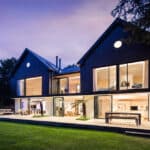 Thumbnail of http://Modern%20two-story%20house%20with%20large%20glass%20windows,%20illuminated%20from%20within.%20It%20sits%20on%20a%20neatly%20maintained%20lawn%20at%20dusk,%20featuring%20outdoor%20seating%20and%20lush%20greenery.