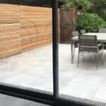 Thumbnail of http://Patio%20with%20a%20glass%20table,%20six%20chairs,%20wooden%20fence,%20and%20sliding%20glass%20door.%20Garden%20with%20greenery%20and%20a%20wooden%20shed%20in%20the%20background.