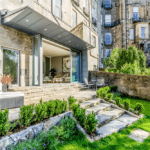 Thumbnail of http://A%20stone%20building%20with%20a%20modern%20patio%20features%20sliding%20doors,%20outdoor%20seating,%20and%20a%20landscaped%20garden%20with%20a%20stone%20path.