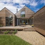 Thumbnail of http://This%20modern%20house%20features%20wood%20paneling%20and%20large%20windows,%20complemented%20by%20a%20gravel%20path.%20The%20deck%20hosts%20an%20outdoor%20dining%20set,%20overlooking%20a%20small%20garden.%20Designed%20to%20be%20flood%20resilient,%20it%20sits%20gracefully%20under%20a%20blue%20sky%20with%20scattered%20clouds%20overhead.