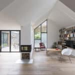 Thumbnail of http://The%20modern%20living%20room,%20designed%20to%20be%20flood%20resilient,%20boasts%20large%20windows,%20a%20fireplace,%20and%20wooden%20floors.%20A%20bookshelf%20beside%20the%20TV%20complements%20various%20chairs%20and%20a%20red%20armchair%20in%20the%20corner.%20In%20the%20background,%20a%20dining%20area%20adds%20to%20its%20appeal.