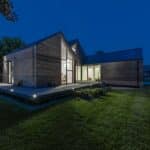 Thumbnail of http://Modern%20wooden%20house%20with%20large%20windows,%20illuminated%20at%20night.%20Surrounded%20by%20a%20well-kept%20lawn%20and%20trees,%20this%20flood-resilient%20home%20features%20an%20angled%20roof%20and%20a%20spacious%20deck,%20effortlessly%20blending%20style%20with%20safety.