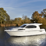 Thumbnail of http://A%20white%20motor%20yacht%20glides%20gracefully%20on%20a%20calm%20river,%20surrounded%20by%20autumn%20trees%20under%20a%20clear%20blue%20sky—an%20idyllic%20scene%20where%20the%20pristine%20beauty%20of%20nature%20meets%20refined%20boat%20elegance.