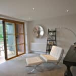 Thumbnail of http://Modern%20living%20room%20with%20two%20white%20chairs,%20a%20curved%20floor%20lamp,%20a%20black%20table,%20metal%20wall%20art,%20and%20a%20shelving%20unit.%20Glass%20doors%20open%20to%20a%20balcony%20with%20outdoor%20seating.