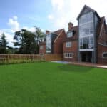 Thumbnail of http://Spacious%20backyard%20with%20lush%20grass%20in%20front%20of%20a%20modern,%20multi-story%20brick%20house%20featuring%20large%20windows%20and%20a%20wooden%20deck.