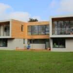 Thumbnail of http://Modern%20two-story%20house%20with%20sf75%20bifold%20doors,%20large%20windows,%20wooden%20cladding,%20and%20a%20flat%20roof,%20set%20in%20a%20grassy%20area.