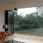 Thumbnail of http://The%20living%20room%20features%20an%20orange%20sofa,%20sunflowers%20on%20the%20table,%20and%20a%20view%20of%20a%20lush%20garden%20through%20sleek%20SF75%20bifold%20sliding%20glass%20doors.