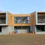 Thumbnail of http://A%20modern%20two-story%20house%20with%20large%20windows%20and%20wooden%20accents,%20featuring%20SF75%20bifold%20doors%20that%20open%20to%20two%20balconies,%20and%20several%20potted%20plants%20on%20the%20ground%20level.