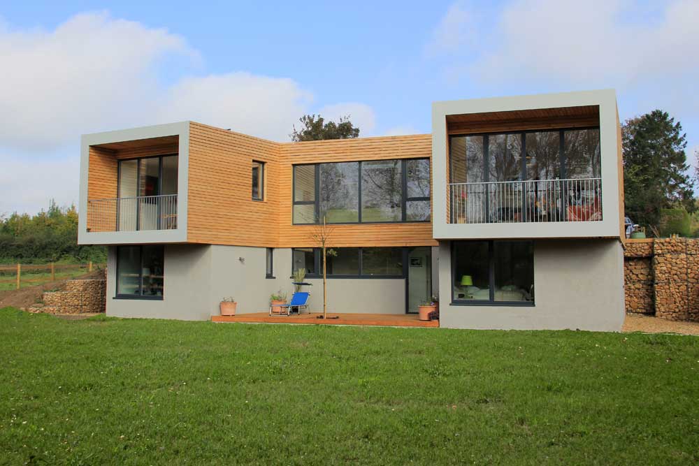 Modern two-story house with sf75 bifold doors, large windows, wooden cladding, and a flat roof, set in a grassy area.