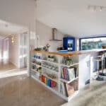 Thumbnail of http://Modern%20kitchen%20with%20a%20central%20island,%20reminiscent%20of%20a%20Grand%20Designs%20feature,%20showcasing%20shelves%20of%20books%20and%20plants.%20It%20includes%20barstools%20and%20large%20windows%20offering%20garden%20views.%20Light%20tiled%20flooring%20and%20white%20walls%20enhance%20the%20bright%20space.