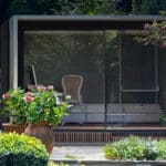 Thumbnail of http://A%20modern%20glass%20garden%20office%20with%20a%20white%20chair%20and%20a%20desk,%20surrounded%20by%20lush%20green%20plants%20and%20colorful%20flowers.