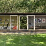 Thumbnail of http://Modern%20garden%20office%20with%20glass%20walls,%20featuring%20a%20desk%20with%20a%20computer,%20a%20gaming%20chair,%20shelves%20with%20books%20and%20decor,%20a%20red%20beanbag,%20framed%20artwork,%20and%20a%20sofa,%20surrounded%20by%20trees%20and%20grass.