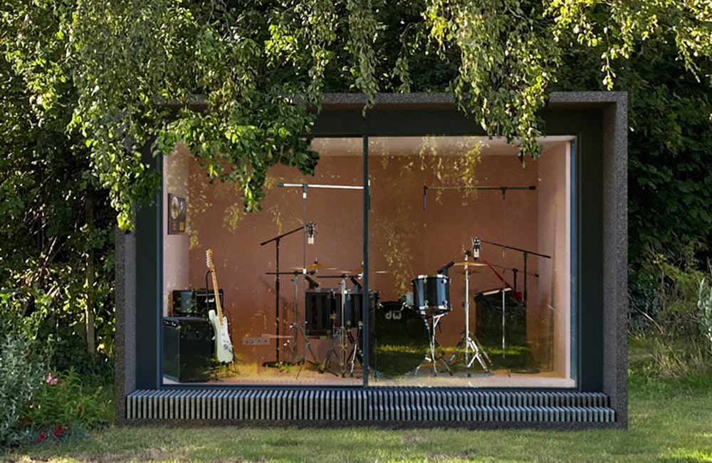 A modern music studio with glass walls, containing a drum set, electric guitar, microphone stands, and various audio equipment, surrounded by lush greenery.