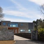 Thumbnail of http://Modern%20brick%20house%20with%20large%20windows%20and%20a%20gated%20entrance,%20surrounded%20by%20trees.