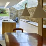 Thumbnail of http://Modern%20kitchen%20with%20skylight,%20wood%20and%20brick%20accents,%20and%20garden%20view.%20Features%20an%20island%20with%20stovetop,%20white%20cabinets,%20and%20triangular%20hanging%20lights.