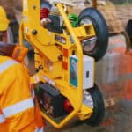 Thumbnail of http://A%20worker%20in%20an%20orange%20safety%20jacket,%20reminiscent%20of%20Grand%20Designs,%20skillfully%20operates%20a%20device%20with%20suction%20cups%20to%20lift%20a%20large%20glass%20panel%20at%20the%20construction%20site.