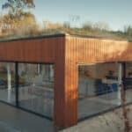 Thumbnail of http://The%20Modern%20wooden%20house,%20reminiscent%20of%20a%20Grand%20Designs%20project,%20features%20large%20glass%20windows%20and%20a%20vibrant%20green%20roof.%20It%20is%20beautifully%20nestled%20among%20trees%20and%20grass%20under%20a%20clear%20sky.