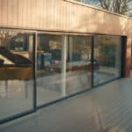 Thumbnail of http://This%20modern%20house,%20reminiscent%20of%20Grand%20Designs,%20boasts%20large%20glass%20doors%20that%20unveil%20an%20interior%20featuring%20a%20grand%20piano%20and%20elegant%20furniture.%20The%20exterior%20is%20beautifully%20complemented%20by%20a%20wooden%20deck%20and%20lush%20surrounding%20greenery.