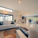 Thumbnail of http://The%20spacious%20living%20room,%20reminiscent%20of%20Grand%20Designs,%20boasts%20white%20sofas,%20a%20round%20rug,%20and%20a%20piano.%20Expansive%20windows%20flood%20the%20space%20with%20natural%20light,%20while%20shelves%20brim%20with%20books%20and%20decor.