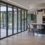 Thumbnail of http://Modern%20kitchen%20with%20a%20large%20island,%20bar%20stools,%20and%20pendant%20lights.%20Floor-to-ceiling%20glass%20doors%20open%20to%20a%20patio%20area.%20Neutral%20tones%20create%20a%20spacious%20and%20airy%20feel.