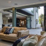 Thumbnail of http://Modern%20living%20room%20with%20beige%20leather%20sofas,%20open%20sliding%20doors%20leading%20to%20a%20patio,%20and%20a%20view%20of%20the%20kitchen%20and%20dining%20area%20in%20the%20background.