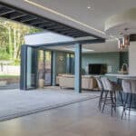 Thumbnail of http://Modern%20open-plan%20kitchen%20and%20living%20area%20with%20bi-fold%20doors%20leading%20to%20a%20patio.%20Light%20wood,%20neutral%20sofas,%20and%20island%20with%20bar%20stools.