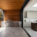 Thumbnail of http://Modern%20kitchen%20with%20sliding%20glass%20doors,%20outdoor%20grill,%20wooden%20ceiling,%20and%20contemporary%20indoor%20fixtures.%20Features%20bar%20stools,%20potted%20plants,%20and%20ample%20natural%20light.