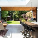 Thumbnail of http://Modern%20kitchen%20with%20an%20open%20layout,%20featuring%20a%20bar%20counter%20and%20dining%20table.%20Glass%20doors%20lead%20to%20a%20garden%20with%20a%20grill%20and%20outdoor%20seating.%20Skylight%20and%20wood%20accents%20add%20natural%20warmth.