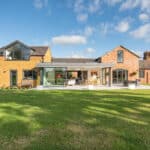 Thumbnail of http://Spacious%20modern%20house%20with%20large%20glass%20windows%20and%20a%20red%20brick%20exterior,%20featuring%20HBD%20Systems'%20sliding%20doors%20and%20a%20stylish%20glazed%20extension.%20It's%20surrounded%20by%20a%20green%20lawn%20under%20a%20blue%20sky%20with%20clouds.