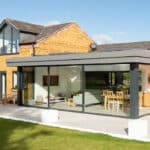 Thumbnail of http://Modern%20house%20featuring%20a%20large%20HBD%20Systems%20glazed%20extension%20with%20sliding%20doors,%20brick%20exterior,%20and%20a%20patio.%20Inside,%20it%20boasts%20a%20dining%20table%20and%20seating%20area%20surrounded%20by%20well-maintained%20grass.