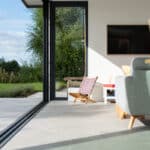 Thumbnail of http://Modern%20living%20room%20with%20sliding%20glass%20doors%20by%20HBD%20Systems%20that%20open%20to%20a%20patio;%20a%20chair%20with%20a%20patterned%20pillow%20basks%20in%20the%20sunlight%20from%20the%20glazed%20extension.