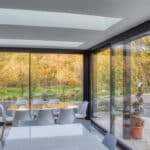 Thumbnail of http://Modern%20dining%20area%20with%20glass%20walls%20and%20ceiling,%20overlooking%20a%20patio%20and%20garden%20with%20trees.