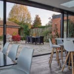 Thumbnail of http://Modern%20dining%20area%20with%20glass%20doors%20opening%20to%20a%20patio.%20The%20outdoor%20space%20includes%20a%20table,%20chairs,%20and%20surrounding%20greenery.