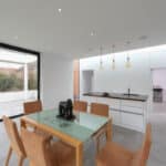 Thumbnail of http://Modern%20dining%20area%20with%20a%20glass%20table%20and%20six%20tan%20chairs,%20next%20to%20an%20open%20kitchen%20with%20a%20black%20countertop.%20Large%20sliding%20glass%20doors%20open%20to%20a%20spacious%20patio.