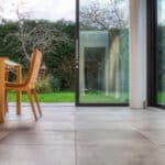 Thumbnail of http://Modern%20room%20with%20large%20glass%20sliding%20doors%20leading%20to%20a%20green%20garden.%20A%20wooden%20chair%20and%20table%20are%20partially%20visible%20on%20the%20left.%20The%20floor%20is%20tiled%20in%20a%20neutral%20color.