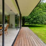 Thumbnail of http://Open%20modern%20living%20space%20with%20sliding%20glass%20doors%20leading%20to%20a%20grassy%20garden.%20Interior%20has%20a%20wooden%20dining%20set%20on%20a%20tiled%20floor,%20and%20an%20exterior%20wooden%20deck%20is%20visible.