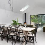 Thumbnail of http://A%20bright%20dining%20room%20with%20a%20long%20wooden%20table,%20black%20chairs,%20and%20a%20potted%20plant.%20Large%20windows%20and%20sliding%20doors%20reveal%20an%20outdoor%20patio%20with%20greenery.%20A%20fireplace%20is%20in%20the%20corner.