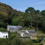 Thumbnail of http://Houses%20with%20stone%20and%20wooden%20exteriors%20surrounded%20by%20trees%20on%20a%20hillside%20under%20a%20clear%20blue%20sky.