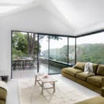 Thumbnail of http://Spacious%20living%20room%20with%20green%20sofas%20and%20a%20wood%20stove,%20large%20sliding%20glass%20doors%20open%20to%20a%20patio%20with%20outdoor%20dining,%20overlooking%20a%20scenic%20view%20of%20hills%20and%20trees.