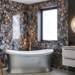 Thumbnail of http://Bathroom%20with%20a%20freestanding%20silver%20bathtub,%20agate-patterned%20wall%20tiles,%20a%20ladder%20shelf%20with%20towels,%20a%20wall-mounted%20sink,%20and%20a%20round%20mirror%20with%20light%20above%20beside%20a%20window%20with%20frosted%20glass.