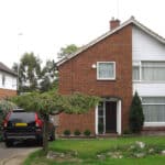 Thumbnail of http://Two-story%20brick%20house%20with%20white%20paneling,%20a%20small%20front%20garden,%20and%20a%20black%20SUV%20parked%20in%20the%20driveway,%20adjacent%20to%20a%20green%20hedge.