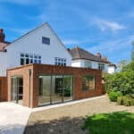 Thumbnail of http://A%20modern%20house%20with%20red%20brick%20and%20white%20facade,%20large%20glass%20doors,%20and%20a%20small%20garden%20under%20a%20clear%20blue%20sky.