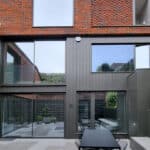 Thumbnail of http://Modern%20brick%20and%20glass%20building%20exterior%20with%20large%20windows%20and%20a%20patio%20featuring%20a%20long%20table%20and%20chairs.