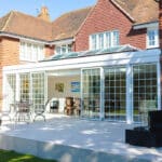 Thumbnail of http://A%20large%20brick%20house%20with%20a%20glass%20conservatory%20and%20sliding%20doors%20opens%20onto%20a%20spacious%20patio%20with%20outdoor%20furniture.