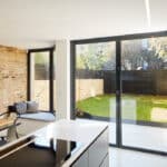 Thumbnail of http://Modern%20kitchen%20with%20an%20island,%20brick%20walls,%20and%20a%20dining%20table.%20Large%20glass%20doors%20open%20to%20a%20small%20grassy%20backyard%20with%20a%20wooden%20fence.