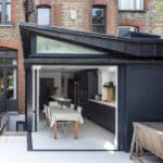 Thumbnail of http://Modern%20kitchen%20extension%20with%20glass%20doors,%20a%20table%20set%20for%20dining,%20and%20sleek%20cabinetry.%20The%20space%20opens%20to%20a%20courtyard%20with%20a%20wooden%20bench%20and%20brick%20walls.