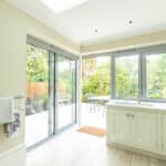 Thumbnail of http://Bright%20kitchen%20with%20light%20cabinetry,%20a%20towel%20rack,%20and%20large%20sliding%20glass%20doors%20leading%20to%20an%20outdoor%20patio%20with%20a%20table%20and%20chairs.%20Greenery%20visible%20through%20the%20glass%20doors.