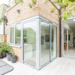 Thumbnail of http://Modern%20brick%20house%20with%20a%20glass-enclosed%20patio%20leading%20into%20an%20open-plan%20interior.%20Potted%20plants%20and%20a%20lattice%20panel%20are%20placed%20beside%20the%20patio.